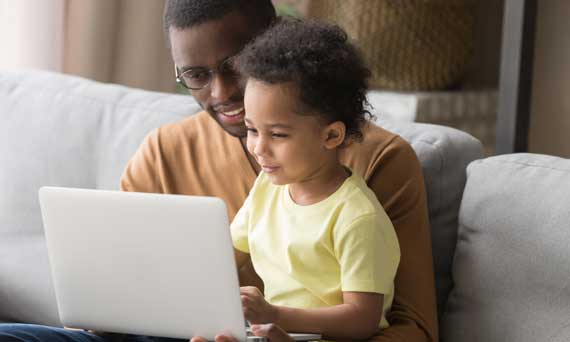 father and son look at laptop computer together