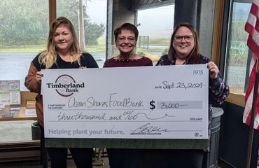 People holding a large ceremonial check from Timberland Bank to the Ocean Shores Food Bank.