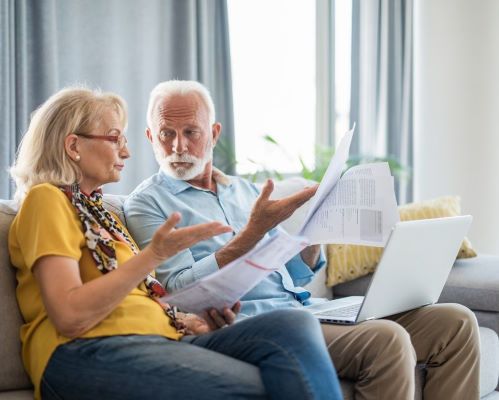 Elderly couple sitting on the couch looking at finances