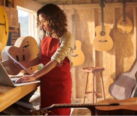 woman applying for a loan on laptop in guitar shop