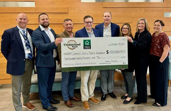 Timberland Bank and Summit Pacific employees posing for a photo with a large check.