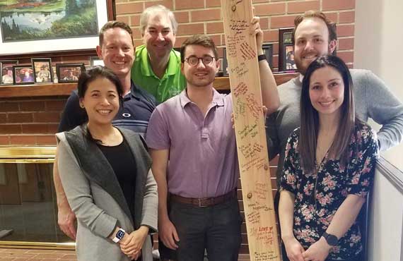 Timberland employees pose with a 2 x 4  for Habitat for Humanity