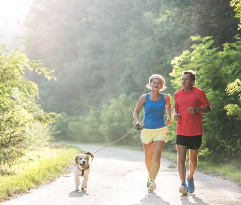 couple and their dog go for a run along a foot path