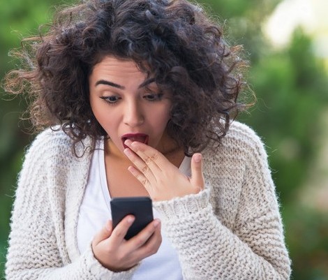 woman looking at mobile phone scared expression