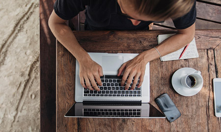 photo taken from above of a man on a laptop with a coffee next to him