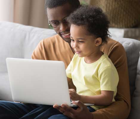father and son look at laptop computer together