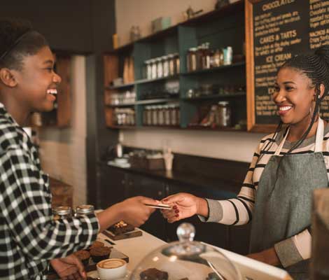 customer at cafe hands debit card to cashier