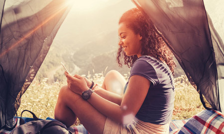 woman in a tent scrolling on her phone