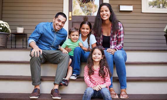 family of 5 poses for a photo on their front porch