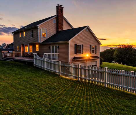 new home in the country with a fenced in yard at sunset