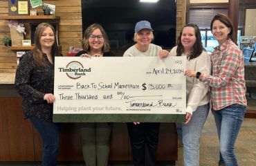 Timberland employees and representatives from Back to School Marketplace holding a large check.
