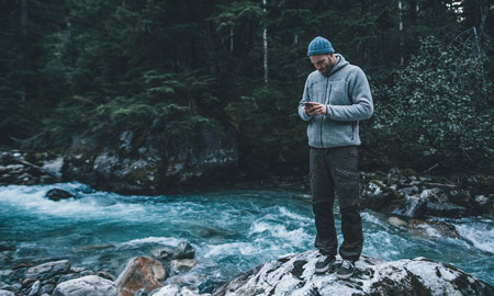 man on a riverbank on his cell phone