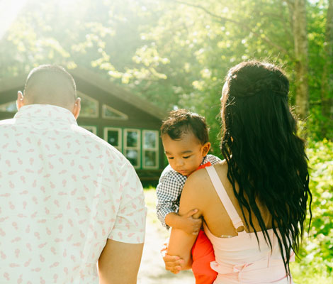 couple holding a baby walking towards a house