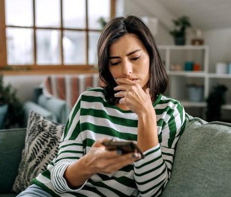 woman looking at smartphone sitting on the couch