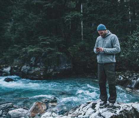 man on a riverbank on his cell phone