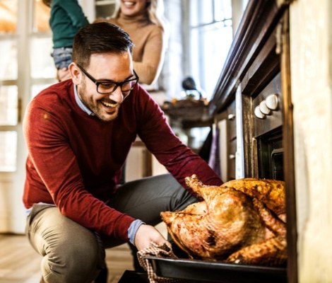 Man taking turkey out of the oven.