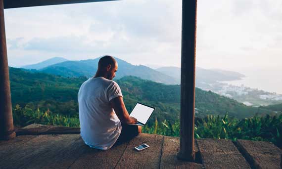 Man on laptop in nature.