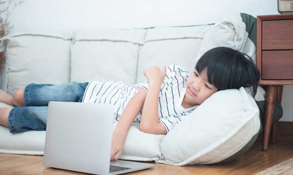 child uses laptop unattended while lounging at home