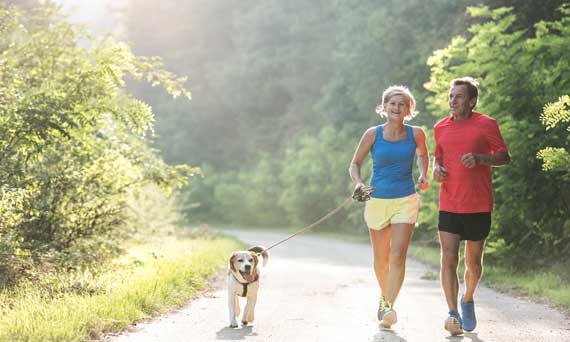 retired couple and dog run on a path