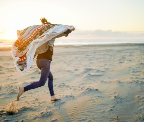 woman runs down the beach at sunrise