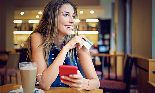 Young woman holding debit card in coffee shop
