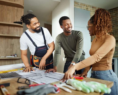 Happy couple looking at blueprints with contractor.