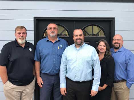 5 people in business casual clothes pose for a group photo